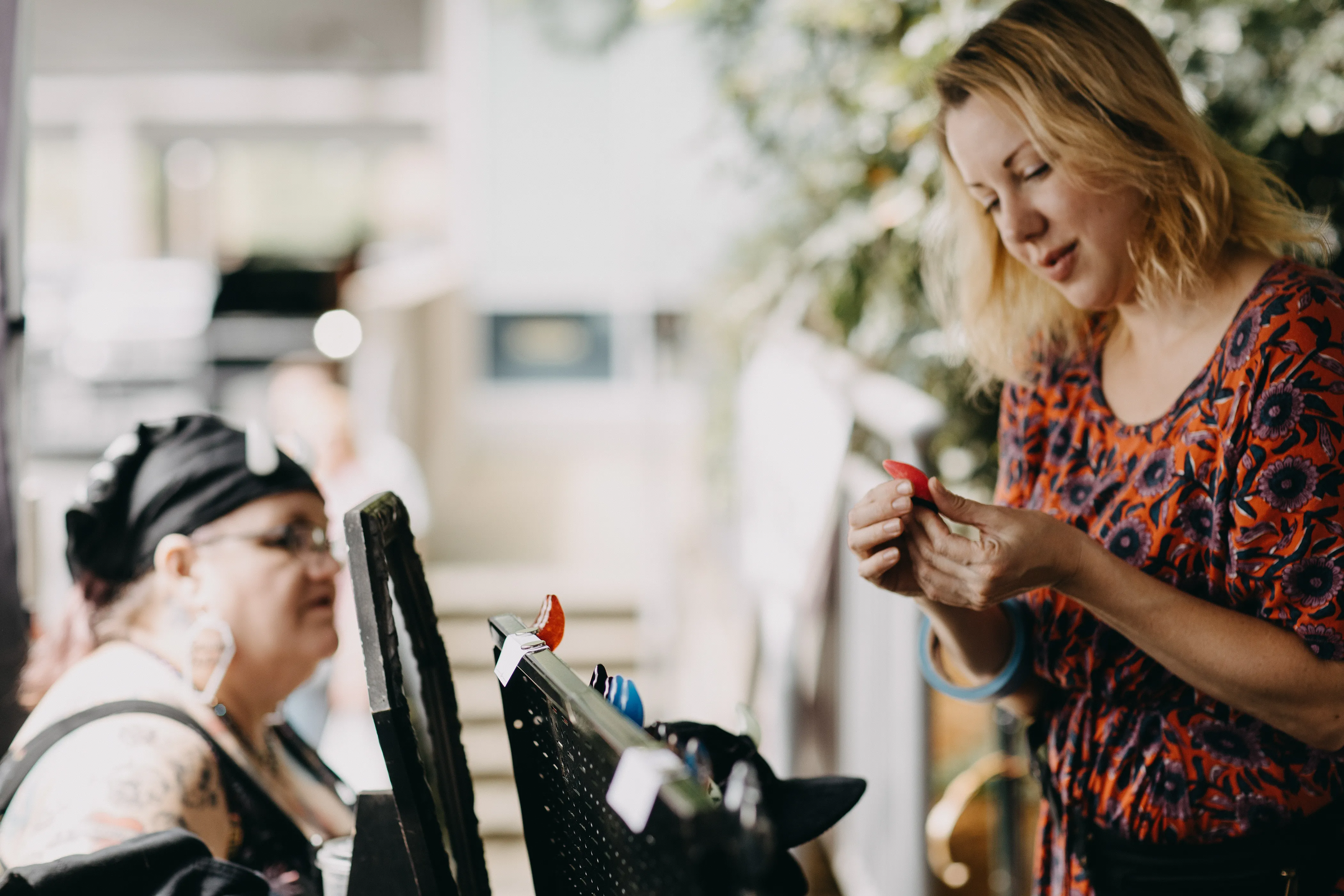 A customer taking a close look at prosthetic horns being sold by a local creator at the Speakeasy Market.