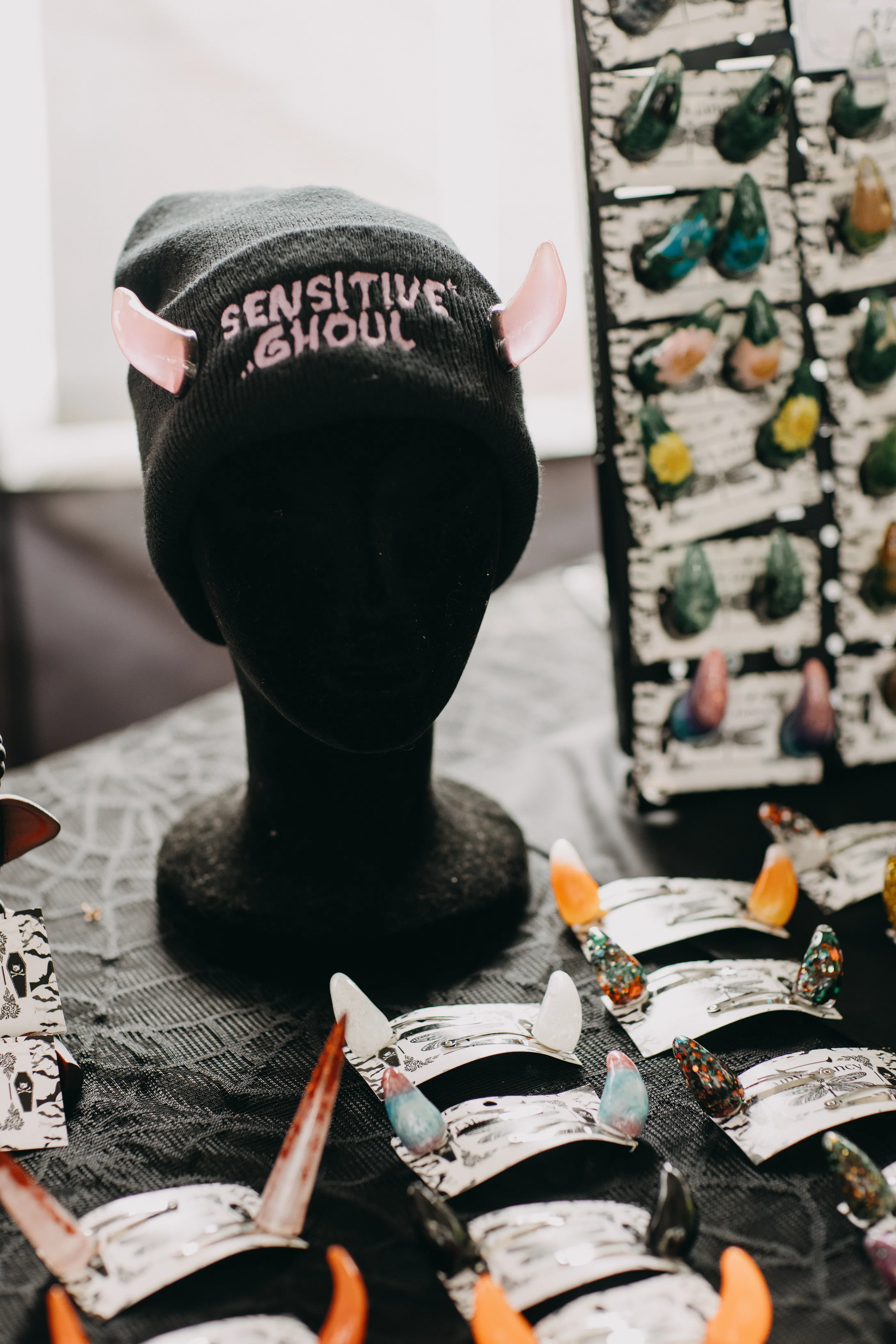 A beanie made for prosthetic horns on a mannequin head with the phrase "Sensitive Ghoul" embroidered onto it.