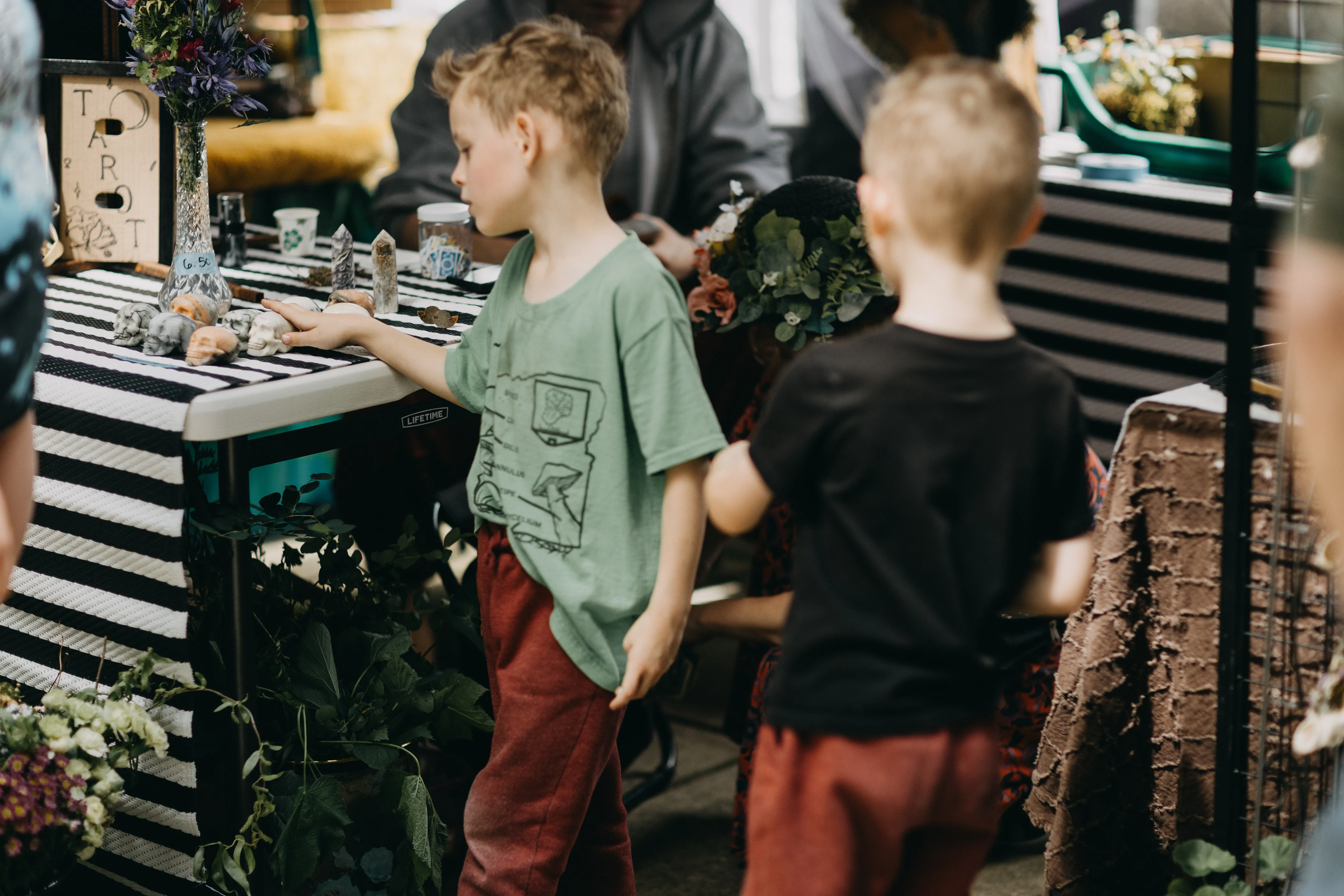 Children fascinated with some skull curios at a vendor table.