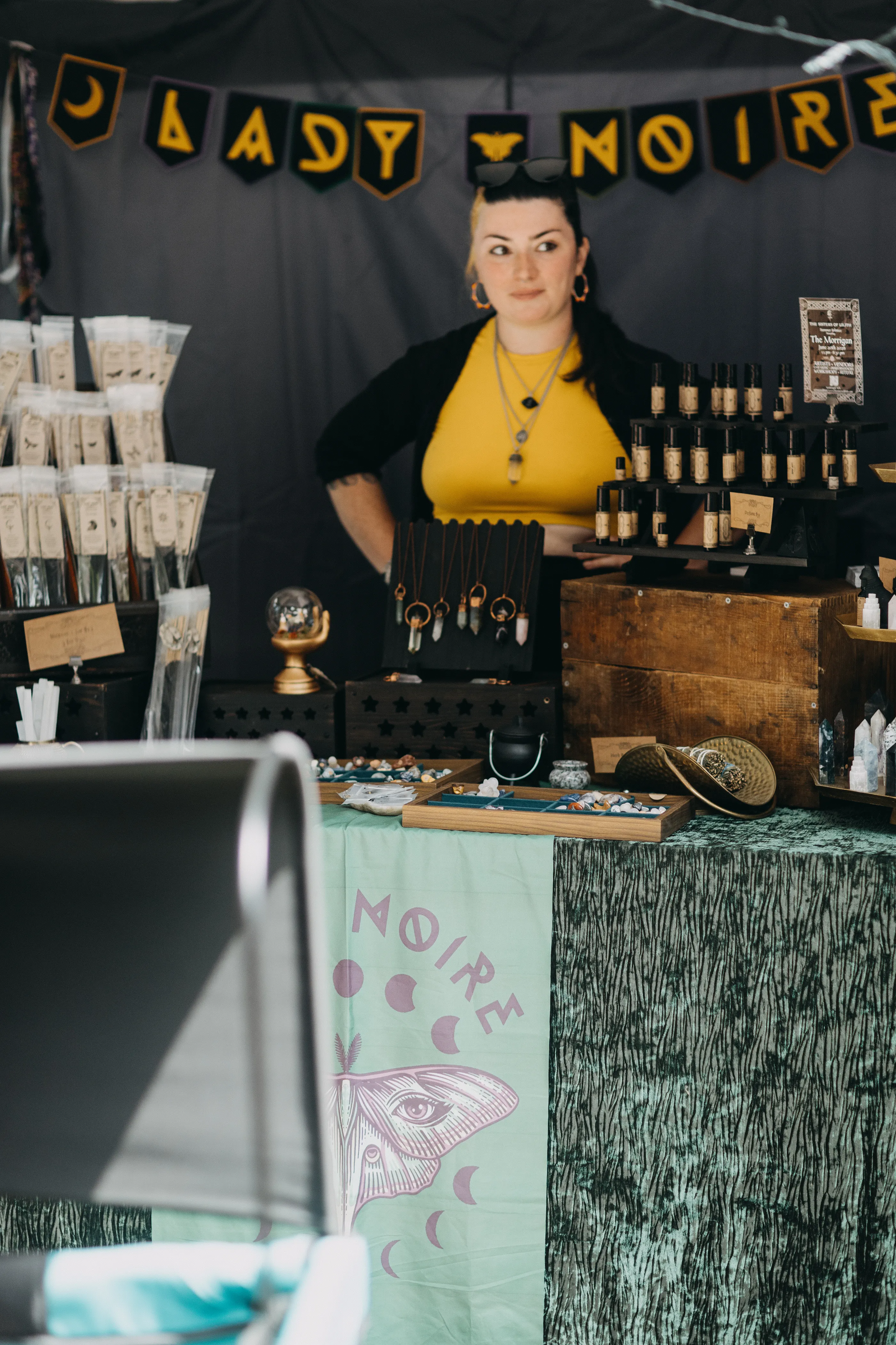 Vancouver's local creative Lady Noire behind a display of polished stones, handmade jewelry, and personally formulated perfumes.