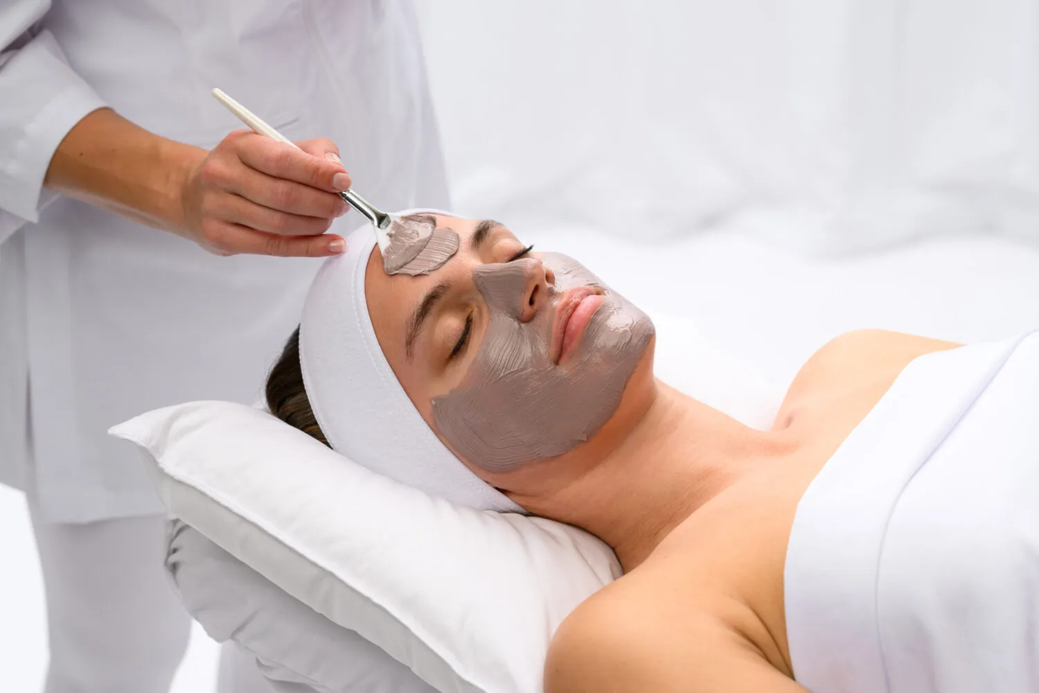 A client receiving a luxury facial treatment mask applied with a brush